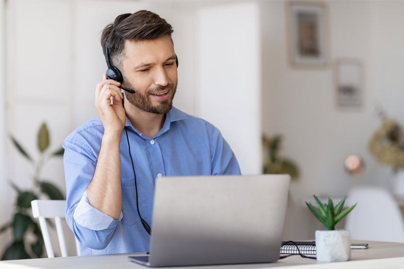 A man doing customer support on a laptop talking into his headset.